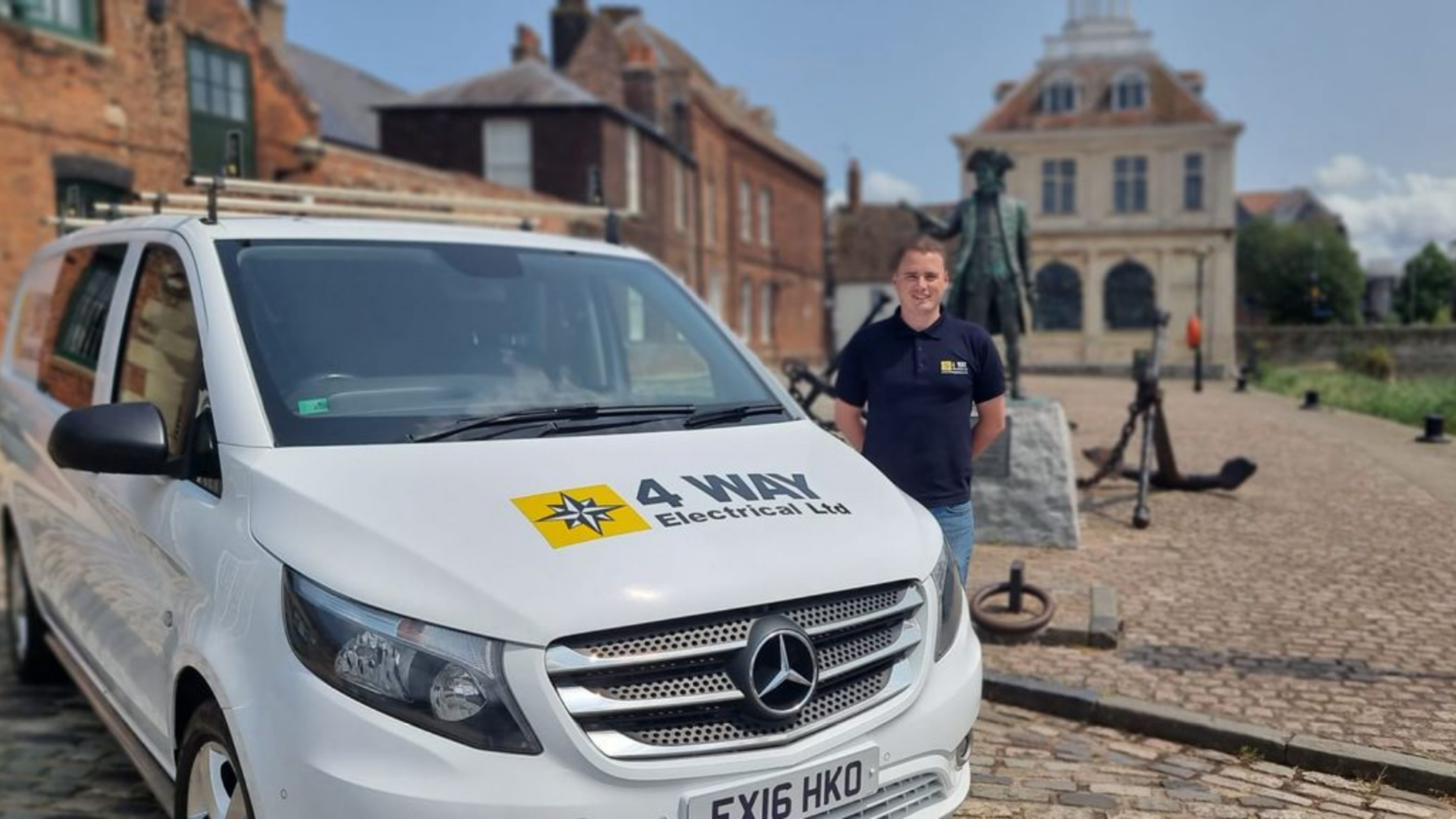 Man next to company van in front of old buildings